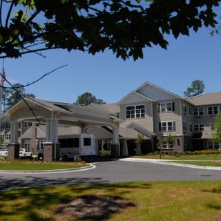 A suburban residential building surrounded by trees under a clear blue sky.