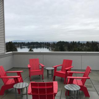 A rooftop terrace with red chairs offers a scenic view of the landscape under an overcast sky.