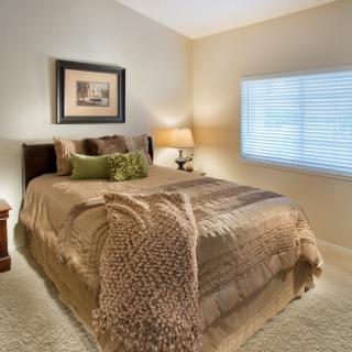 A cozy bedroom with a neatly made bed and warm decor.