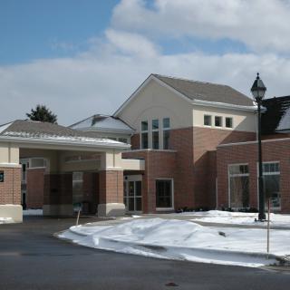 A brick commercial building with a covered entrance, surrounded by snow in winter.
