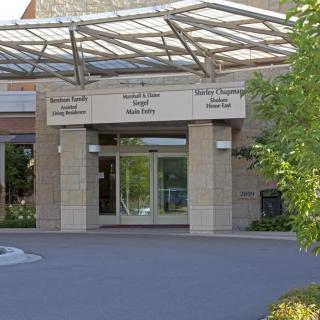 Entrance to a hospital building with visible signs for various departments.