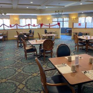 An empty dining area with neatly arranged tables and chairs, featuring decorative elements.