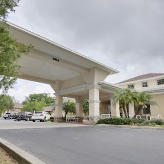 A modern hotel entrance with covered parking under a cloudy sky.