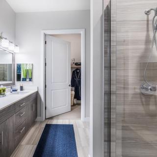 A modern bathroom with a sleek vanity, large mirror, and tiled shower area.