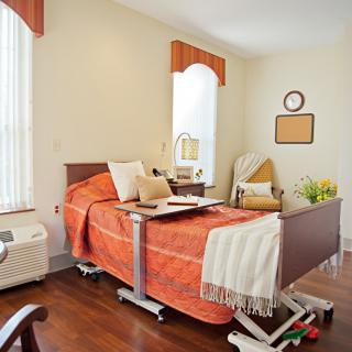 A well-decorated hospital room with an adjustable bed and warm orange accents.