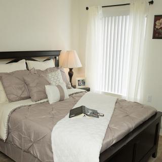 A cozy bedroom with a neatly made bed and soft lighting.