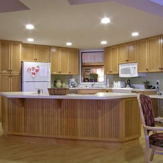 A cozy kitchen featuring wood cabinets and a central island counter with modern lighting.