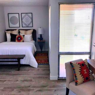 A modern bedroom with a neatly made bed, colorful pillows, and stylish decor.