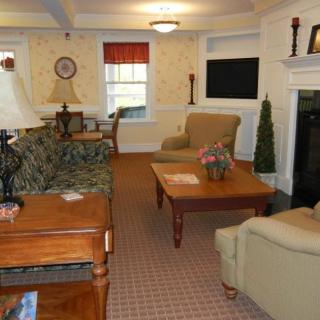 A cozy living room featuring a sofa set, coffee table, lamps, and a fireplace.