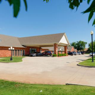 A building with a covered driveway, surrounded by trees on a sunny day.