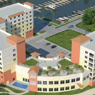 An aerial view of a modern apartment complex with a landscaped courtyard and nearby marina.
