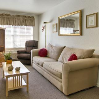 A cozy living room with a beige sofa, armchair, and coffee table adorned with decor.