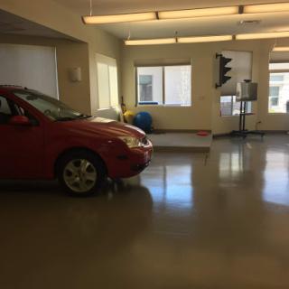 A red car parked inside a spacious garage with ample natural light.