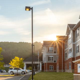 A residential building at sunset with a parking lot and lush surroundings.