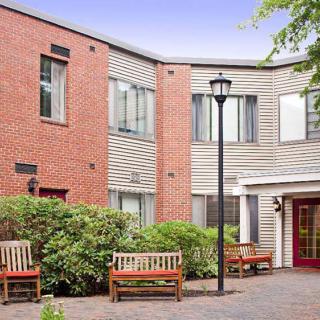 A tranquil courtyard with benches in front of a modern brick and siding building.