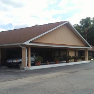 A view of a single-story building with a car parked outside, set against a partly cloudy sky.