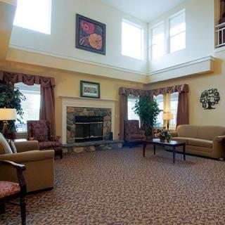 A cozy living room with a fireplace, sofas, armchairs, and large windows.