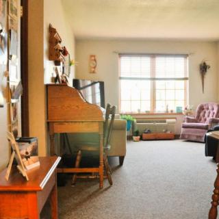 A cozy living room with a piano, sofa, and large window providing natural light.