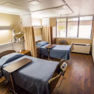 A hospital room with two beds separated by curtains.