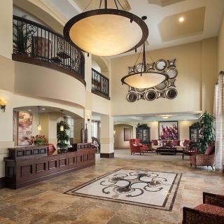 A spacious and elegantly decorated lobby featuring chandeliers, a reception desk, and modern furnishings.