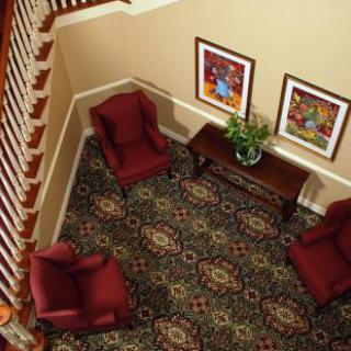 A cozy living room corner with red armchairs, patterned carpet, and framed artwork.