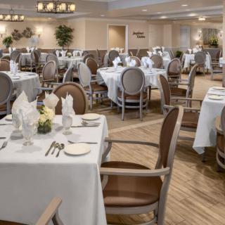 An elegant restaurant dining room with neatly arranged tables and chairs, adorned with white tablecloths and tasteful place settings.