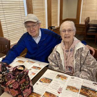 An elderly couple enjoys a meal together at a cozy restaurant.