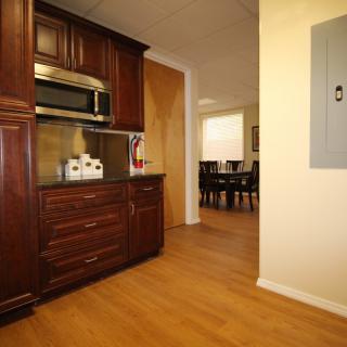 A view of a kitchen with dark wooden cabinetry leading to a dining area.