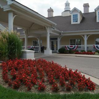 A landscaped entrance with red flowers leading to a building.