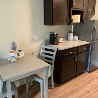 Small kitchen area with a table and chairs, dark cabinets, and appliances including a fridge and coffee maker.