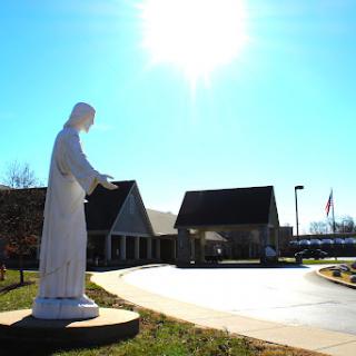 A serene statue in front of a building, basking in sunlight.