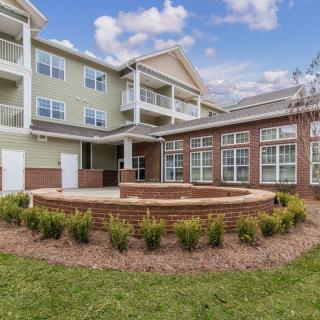 A modern residential apartment building with landscaped gardens and outdoor seating area.