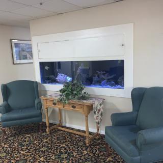 A cozy waiting room with an aquarium and comfortable seating.
