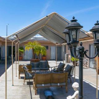 An outdoor patio area featuring a comfortable seating arrangement under a canopy, with decorative lanterns and a potted palm plant.