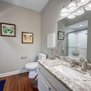 A modern bathroom with a granite countertop, decorated with framed artwork and bright lighting.