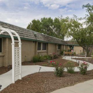 A single-story house with a landscaped garden and pathway featuring an arched trellis.