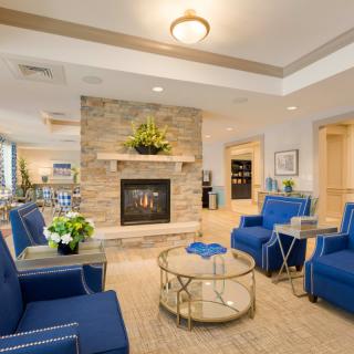 A modern living room with blue chairs and a stone fireplace, featuring elegant interior design.