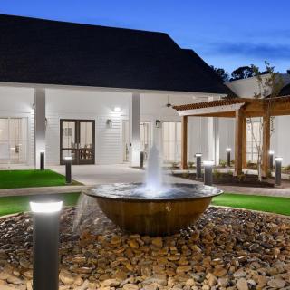 A beautifully lit courtyard at night featuring a central fountain surrounded by modern architecture.