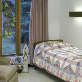 A cozy bedroom with a quilted bedspread and large window.