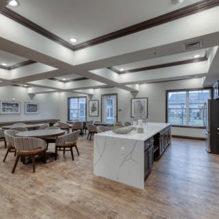 A modern open-concept dining and kitchen area with a sleek marble island and wooden flooring.