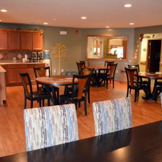 A cozy dining area with wooden tables and chairs, adjacent to a kitchen.