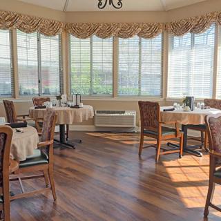 Sunlit dining room with neatly arranged tables and chairs.