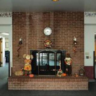 A brick fireplace adorned with autumn decorations, including scarecrow figures and pumpkins.