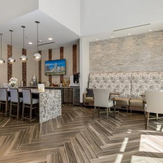A modern lounge area featuring a bar counter with pendant lights and herringbone flooring.