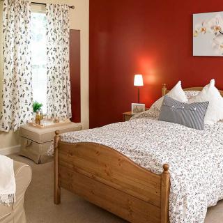 A cozy bedroom with a wooden bed and red accent wall.