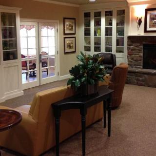A cozy living room with a sofa, fireplace, and French doors leading to another room.