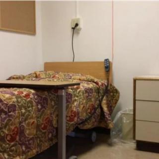 A hospital room with a bed and bedside table.