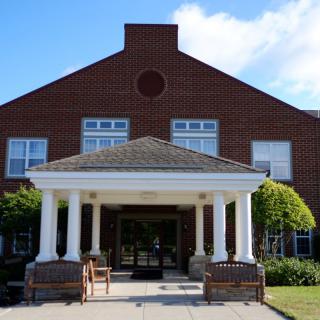 A brick building with a columned entrance and a porch area.