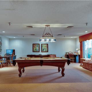 A spacious billiards room featuring a pool table under elegant lighting.