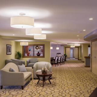 A modern lounge area with comfortable seating and a conference room in the background.